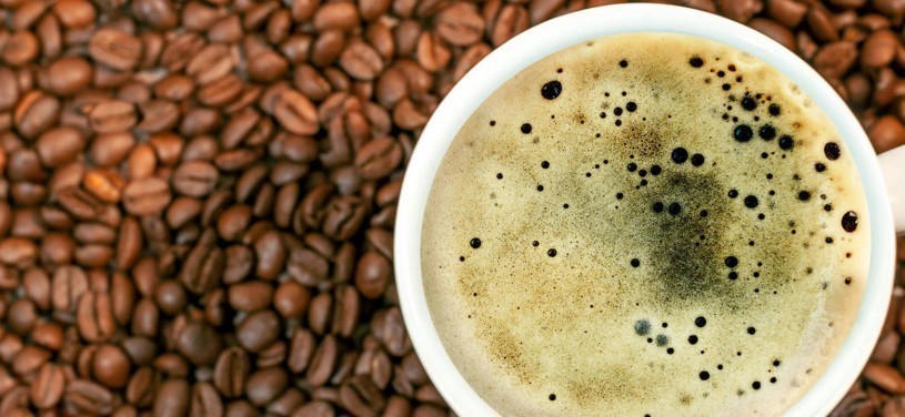 Kaffeebohnenhintergrund mit einer Tasse frischem, heissen Kaffee