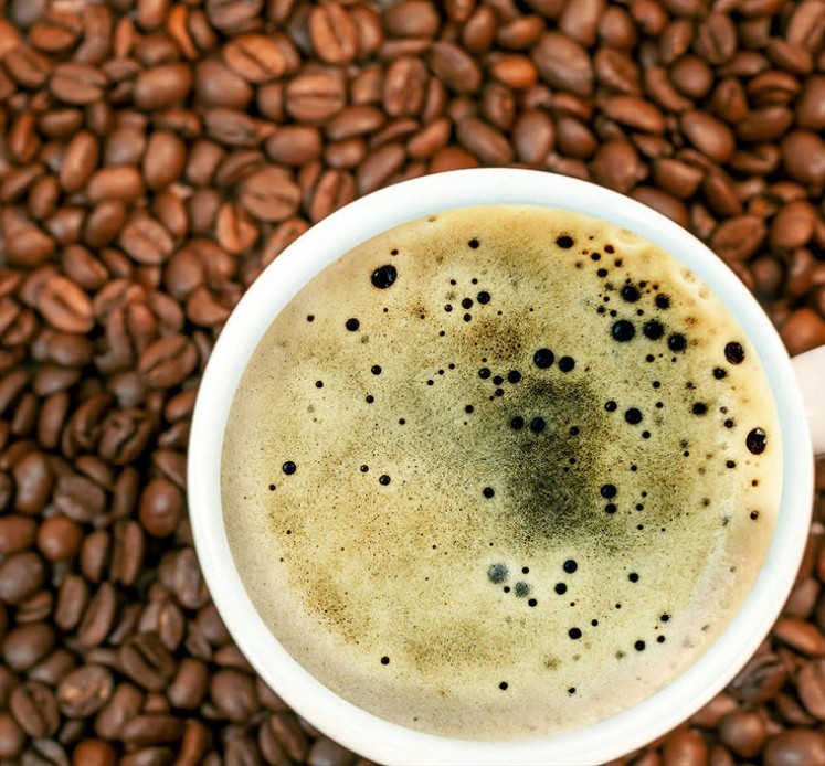 Kaffeebohnenhintergrund mit einer Tasse frischem, heissen Kaffee