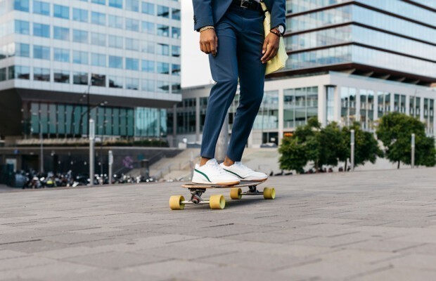Spanien, Barcelona, Beine eines jungen Geschäftsmannes beim Skateboardfahren in der Stadt